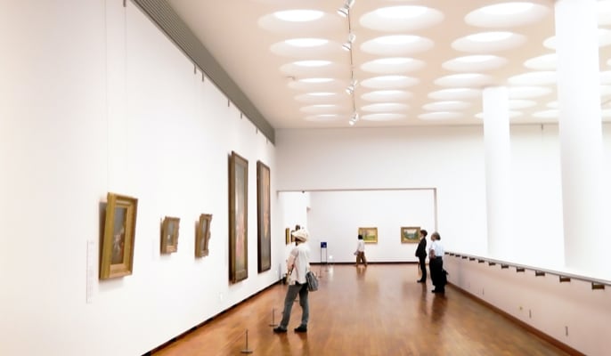 A corridor with people looking at the painting on the wall