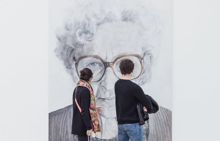 A couple looking at a painting of an old woman